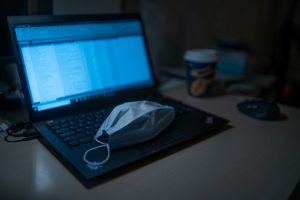 Photo of surgical face mask and a laptop computer.